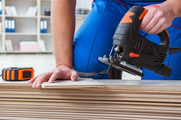 Giovane lavoratore che lavora su pavimenti in laminato — Foto Stock