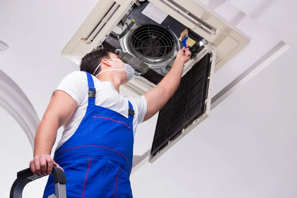 Worker repairing ceiling air conditioning unit — Stock Photo, Image