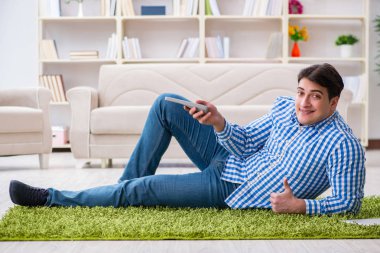 Genç yakışıklı adam evde yerde oturuyor.