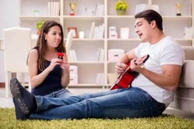 Yerde gitar çalan romantik bir çift.