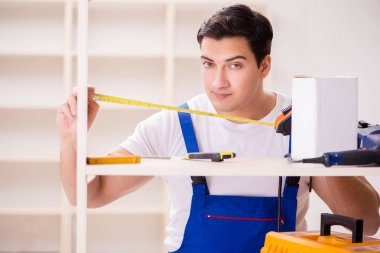 İşçi adam montaj kitaplığını tamir ediyor