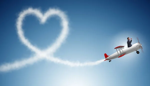 Mann fliegt Flugzeug und macht Herzform — Stockfoto