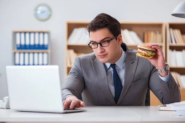 Hambriento empresario divertido comer sándwich de comida chatarra — Foto de Stock