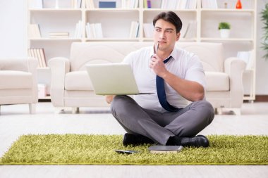 İş adamı ofiste yerde oturuyor.