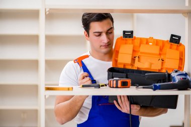 İşçi adam montaj kitaplığını tamir ediyor