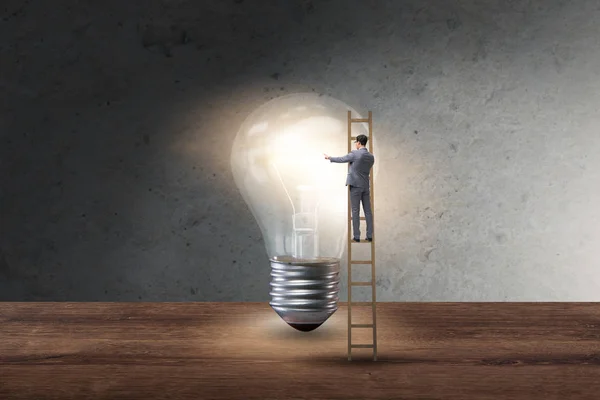 Businessman on ladder with light bulb — Stock Photo, Image