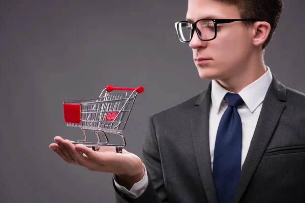 Geschäftsmann mit Einkaufswagen auf grauem Hintergrund — Stockfoto