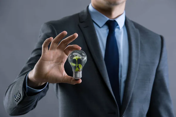 Businessman holding lamp in green environment concept — Stock Photo, Image