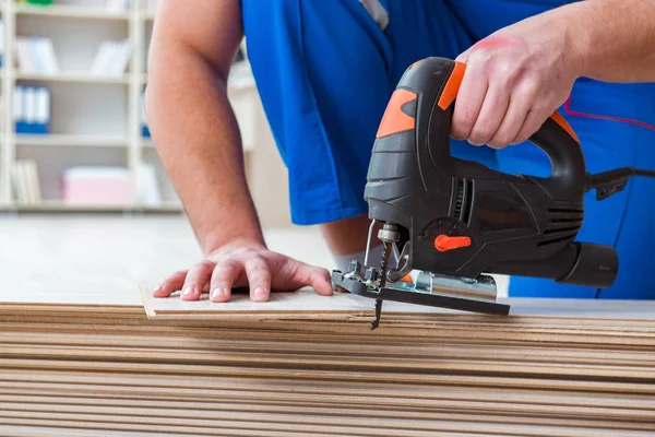 Giovane lavoratore che lavora su pavimenti in laminato — Foto Stock