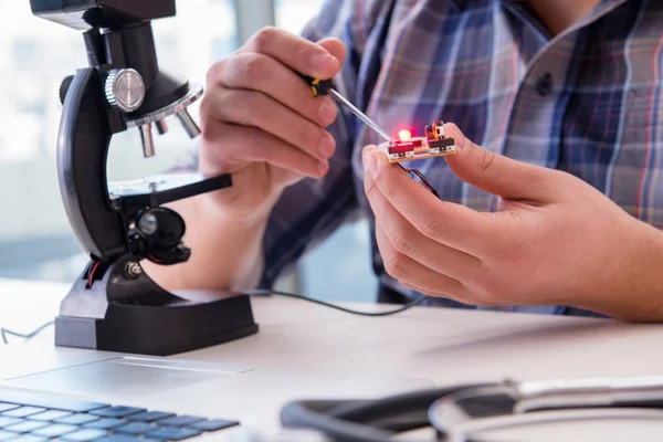 Hohe Feinmechanik mit Menschen, die unter dem Mikroskop arbeiten — Stockfoto