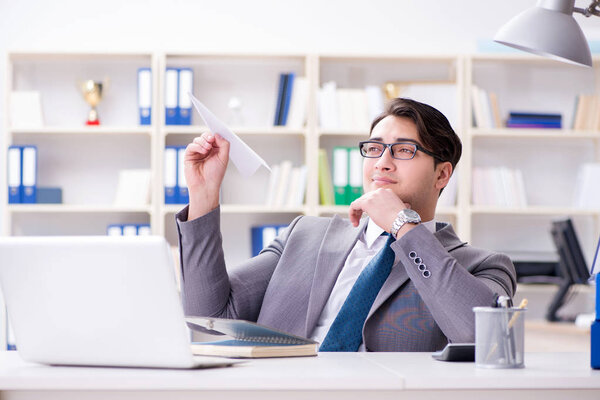 Бизнесмен с бумажным самолетом в офисе