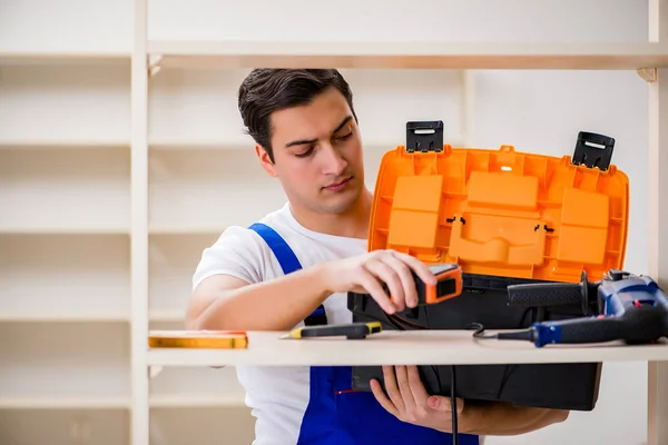 Trabalhador reparando montagem estante de livros — Fotografia de Stock