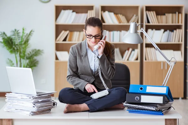 Busy angry businesswoman sitting on the desk in office — Stock Photo, Image