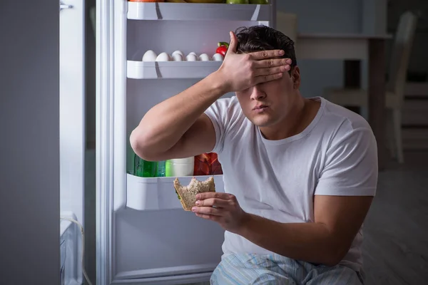 Man at the fridge eating at night — Stock Photo, Image