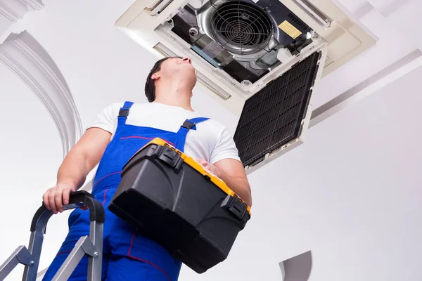 Worker repairing ceiling air conditioning unit