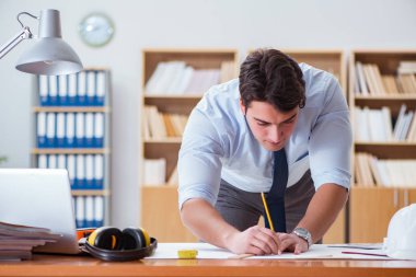 Ofiste çizimler üzerinde çalışan bir mühendis.