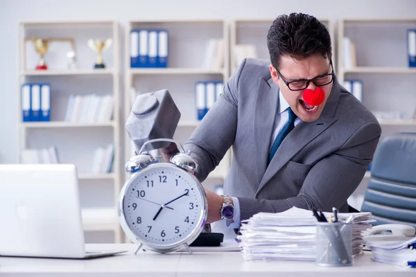 Ofiste çekiç ve çalar saatle palyaço işadamı var.