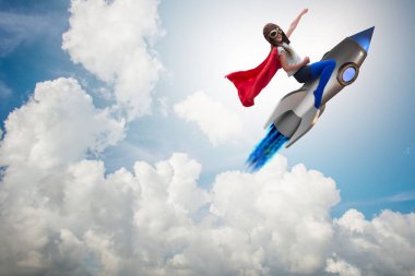 Süper kahraman kavramında küçük bir kız roket uçuruyor.