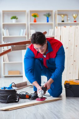 Genç marangoz ahşap kalaslarla çalışıyor.