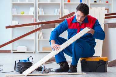 Genç marangoz ahşap kalaslarla çalışıyor.