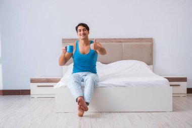 Genç adam yatakta uyanıyor.