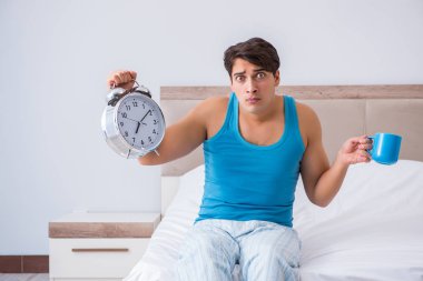 Genç adam yatakta uyanıyor.