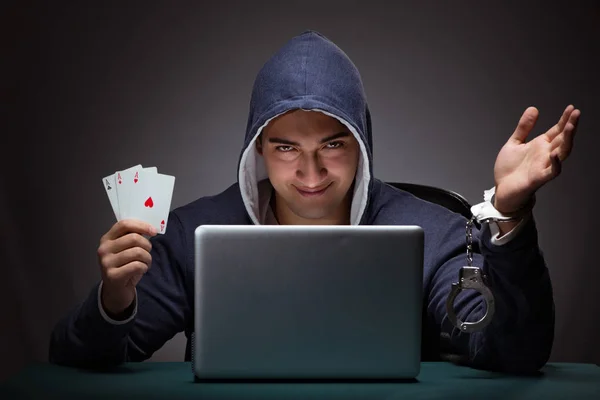 Young man in handcuffs wearing a hoodie sitting in front of a la — Stock Photo, Image