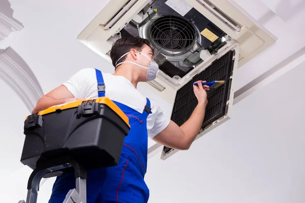 Worker repairing ceiling air conditioning unit — Stock Photo, Image