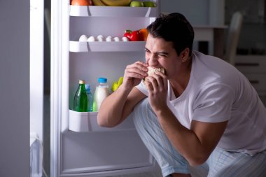 Buzdolabındaki adam gece yemek yiyor.
