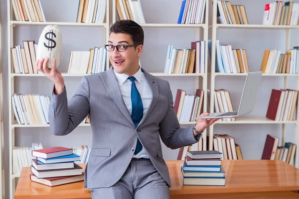 Affärsman i biblioteket med en pengasäck och en laptop — Stockfoto