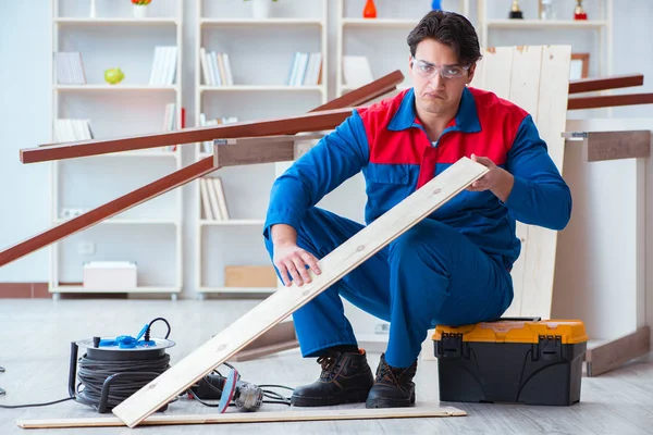 Genç marangoz ahşap kalaslarla çalışıyor.