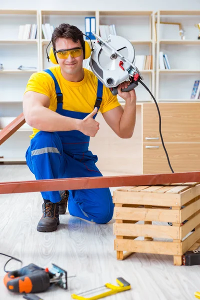 Reparatör snickare skära sågning en träplanka med en cirkulation — Stockfoto