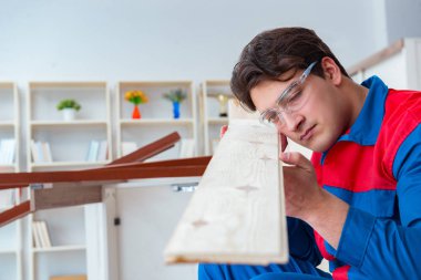 Genç marangoz ahşap kalaslarla çalışıyor.