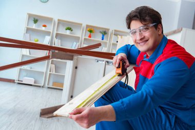 Genç marangoz ahşap kalaslarla çalışıyor.