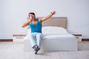 Genç adam yatakta uyanıyor.