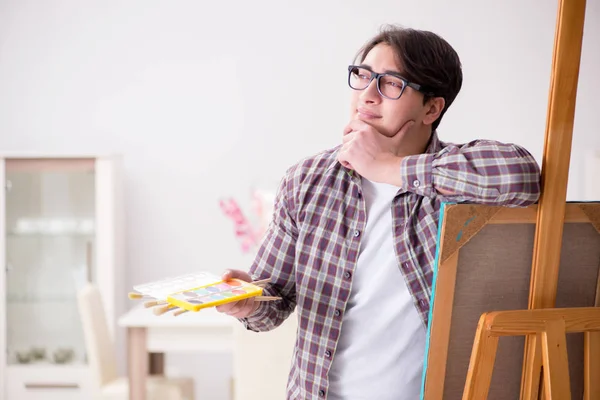 Young male artist drawing pictures in bright studio