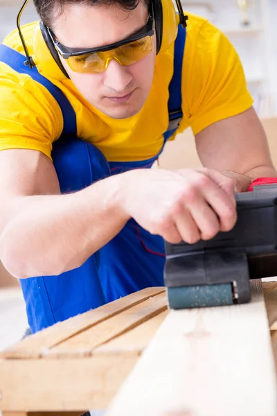 Reparador carpinteiro polir uma placa de madeira com um po elétrico — Fotografia de Stock