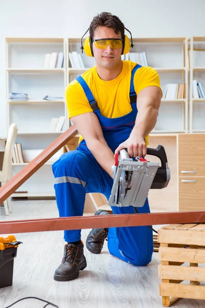 Reparador carpintero cortando aserrar una tabla de madera con un circuito — Foto de Stock