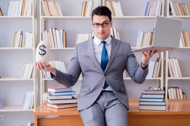 Kütüphanede para çantası ve dizüstü bilgisayarı olan bir iş adamı.