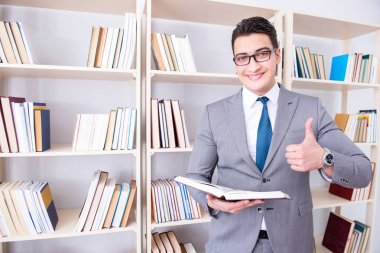 İşadamı öğrenci kütüphanede bir kitap okuyor.