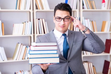 Kütüphanede çalışan yığınla kitabı olan bir işletme hukuk öğrencisi.