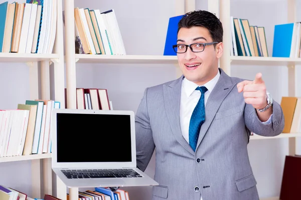 Empresario con un portátil de pantalla en blanco que trabaja en la biblioteca — Foto de Stock