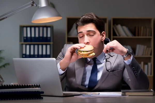 Uomo d'affari a tarda notte mangiare un hamburger — Foto Stock