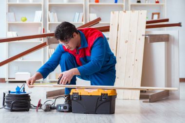 Genç marangoz ahşap kalaslarla çalışıyor.