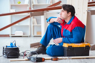 Genç marangoz ahşap kalaslarla çalışmaya ara veriyor.