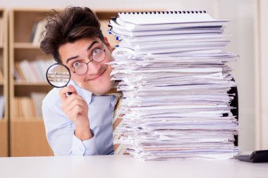 Komik denetçi büyüteçle raporları kontrol ediyor