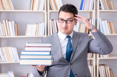 Kütüphanede çalışan yığınla kitabı olan bir işletme hukuk öğrencisi.