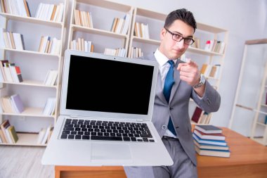 Kütüphanede çalışan boş ekran bilgisayarı olan bir iş adamı.