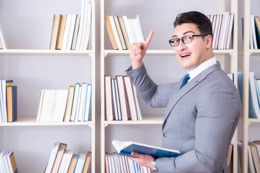 İşadamı öğrenci kütüphanede bir kitap okuyor.