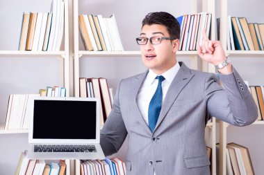 Kütüphanede çalışan boş ekran bilgisayarı olan bir iş adamı.